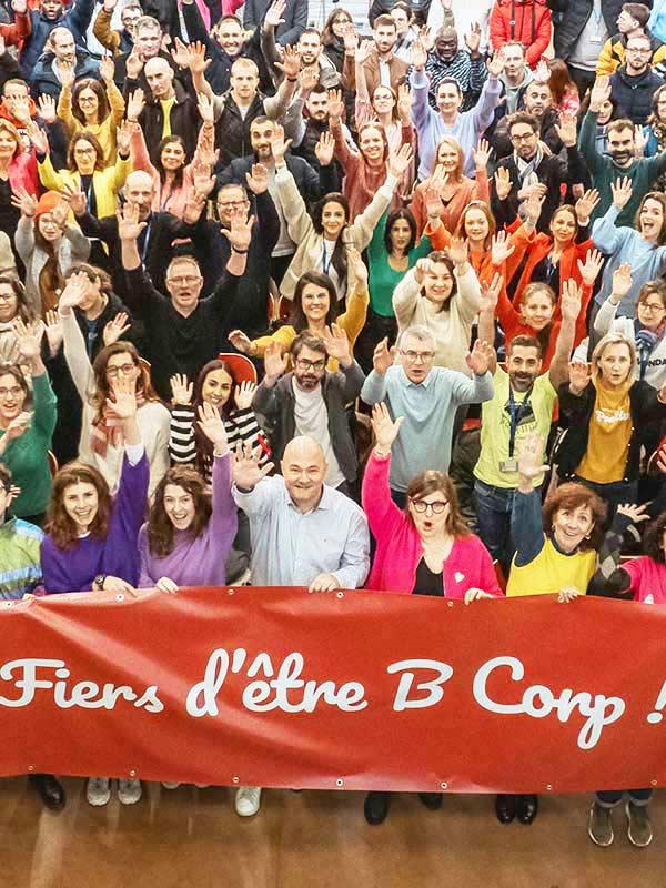 B Corp olmaktan gurur duyuyoruz pankartı taşıyan bir grup Expanscience çalışanı