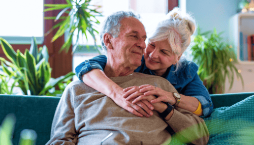 Couple souriant s'enlaçant sur un canapé vert