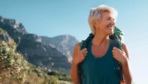 Une femme en randonnée, souriant devant des montagnes