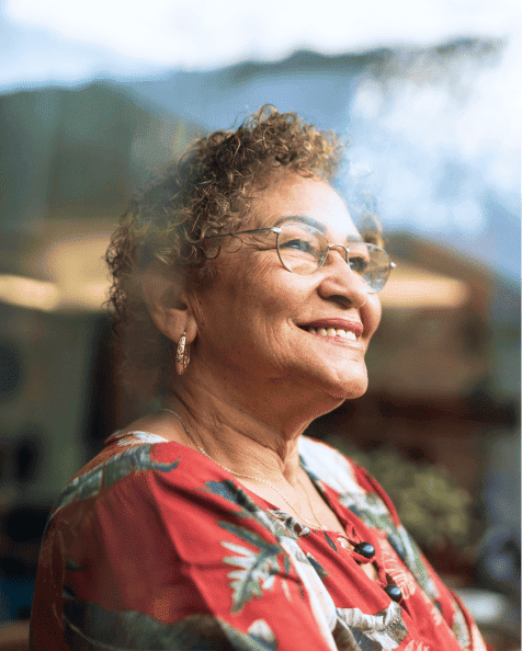 Femme âgé souriante regardant par la fenêtre