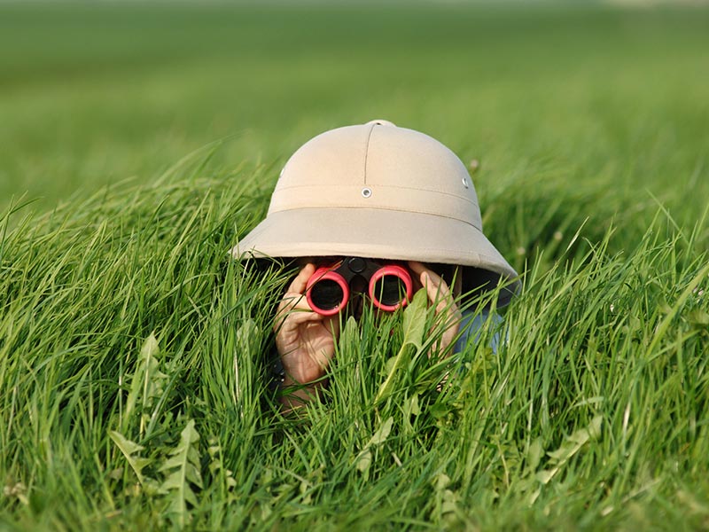 Enfant allongé dans l'herbe avec un casque sur la tête et des jumelles rouges